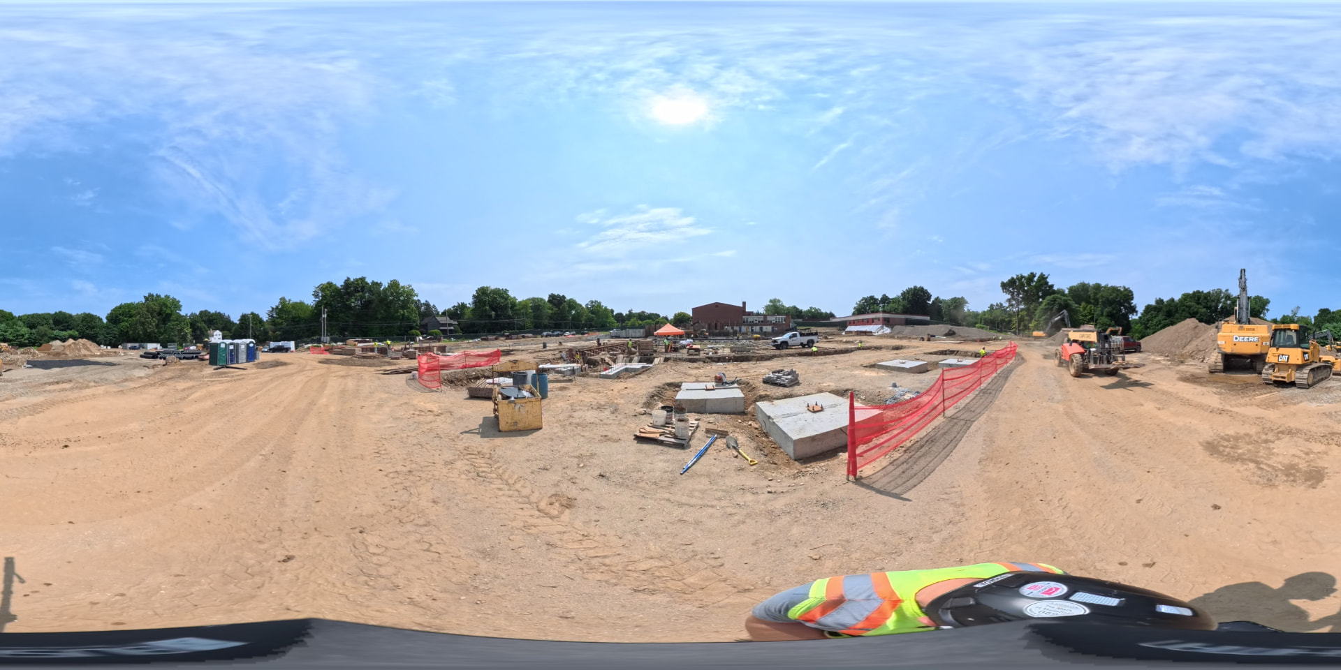 August 2026 — Full-site panorama showing footings, concrete pads and heavy equipment working the length of the new building footprint