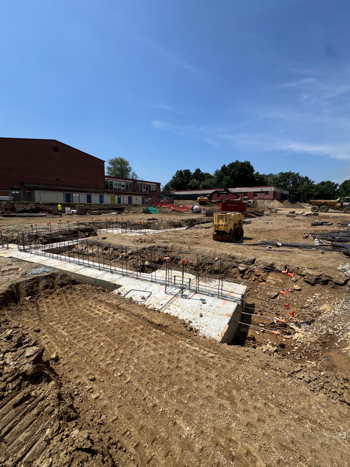 July 2026 — Poured footings and rebar alongside the existing school