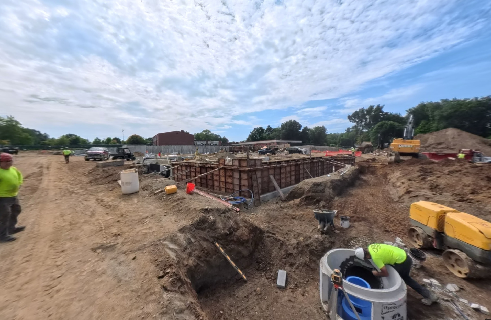September 2026 — Foundation wall formwork and underground utility work progressing near the northeast corner.