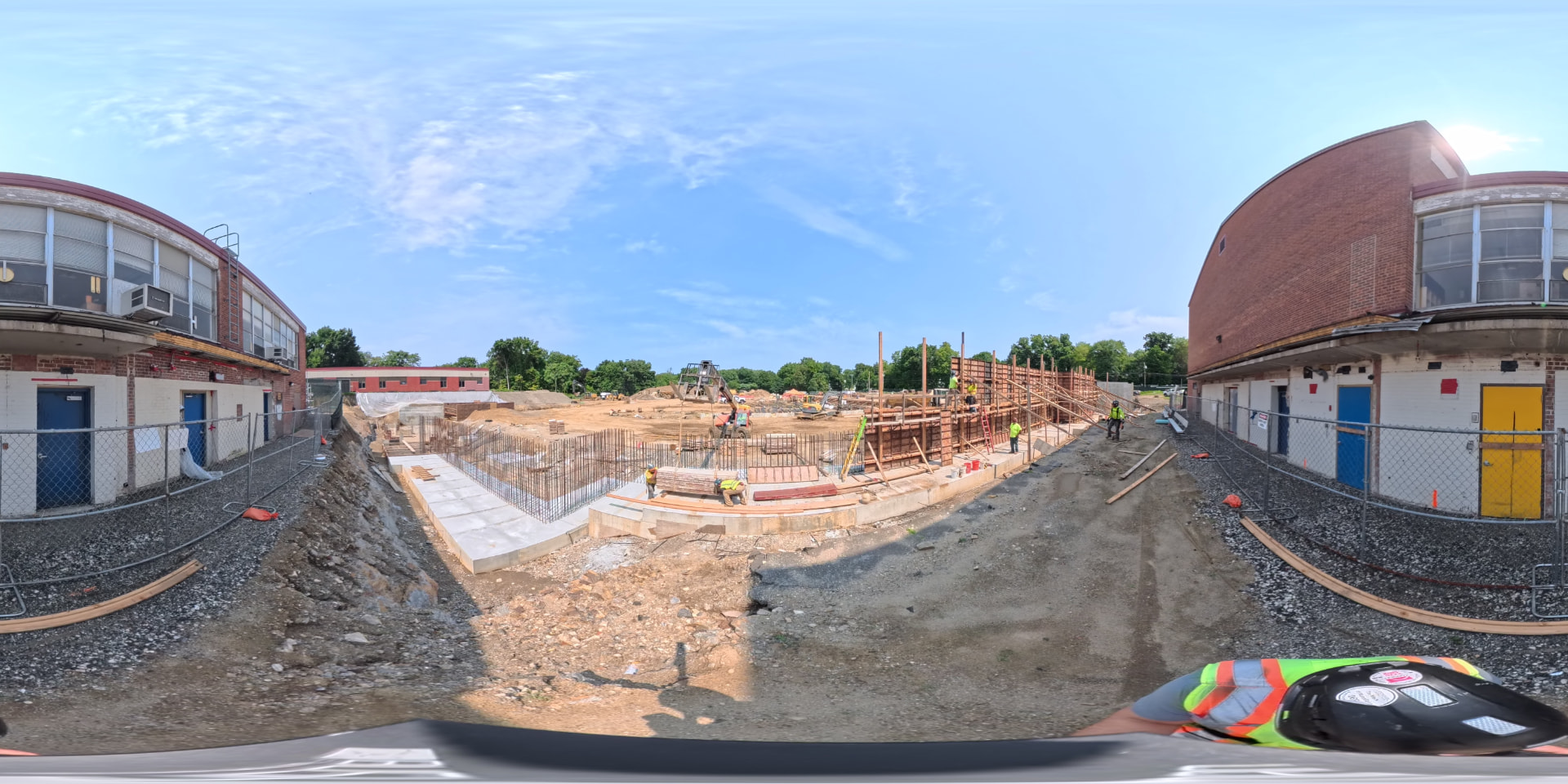 August 2026 — 360° view between the existing school wings and formed foundation walls